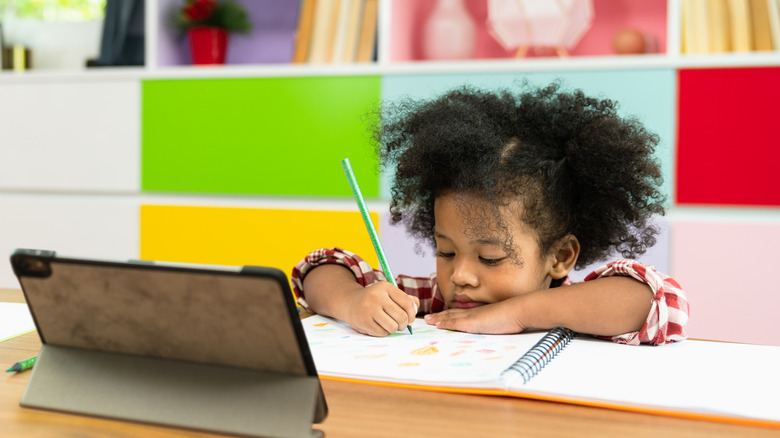 Bored child coloring in notebook