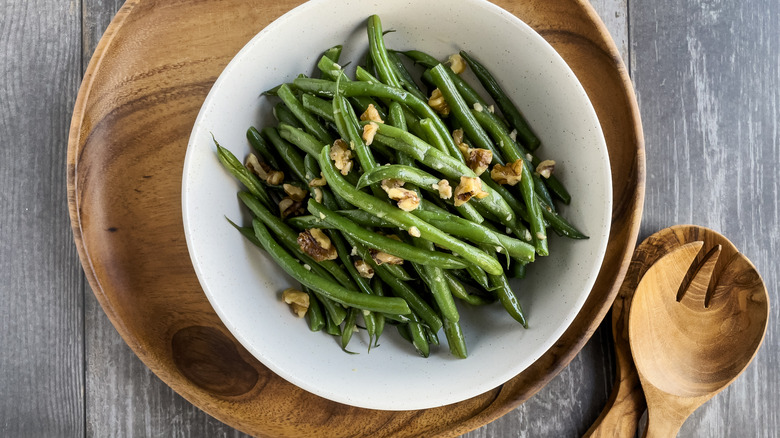 A bowl of green beans topped with sliced almonds