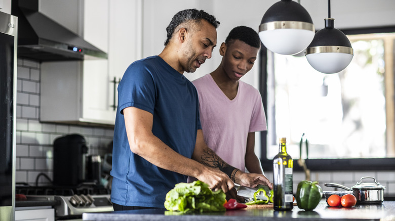 A father and teenage son cooking in the kitchen