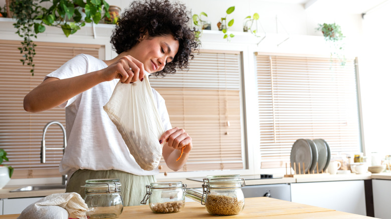 A woman sorting chickpeas into glass jars