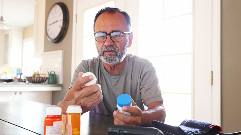 A man looking at his medication bottles