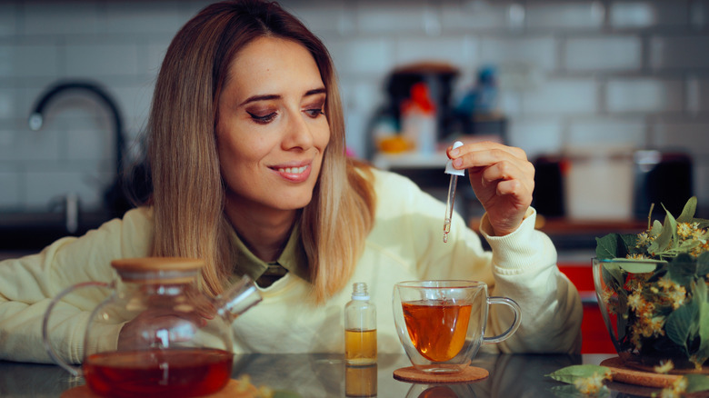 A woman using a dropper to sweeten her tea