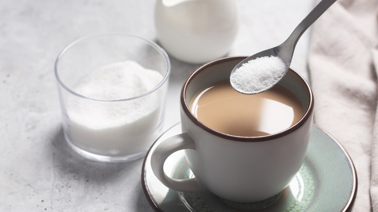 A woman's hand adding some stevia to her coffee