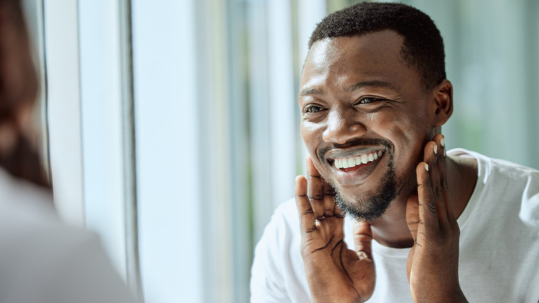 smiling man looking at himself in the bathroom mirror