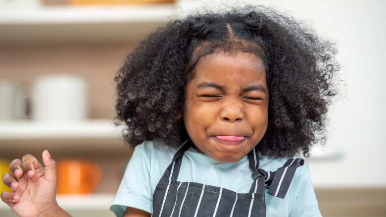 girl making a face after trying a sour food