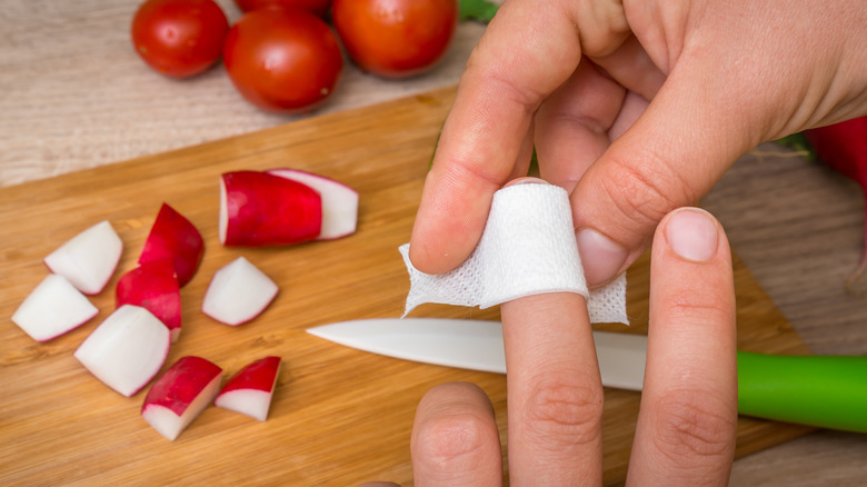 woman putting bandage on cut finger