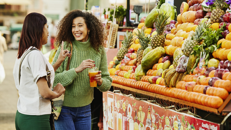 women shopping and talking at outdoor fruit stand
