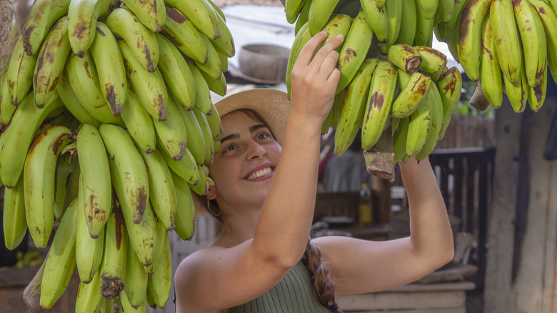 woman with green plantains in outdoor market