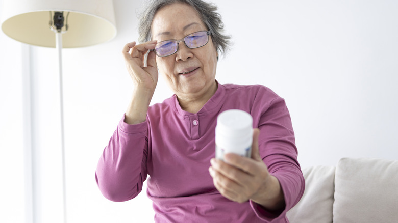 senior woman looking closely at bottle of supplements
