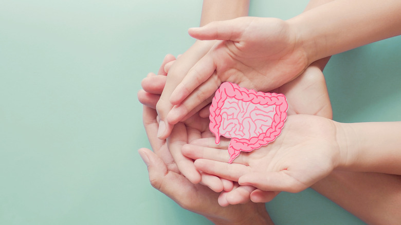 Three people holding a paper colon illustration in their hands