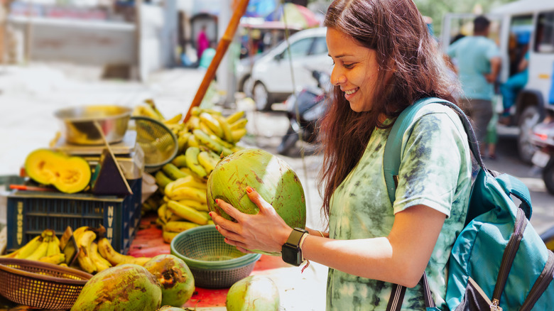 woman buying a coconut at an outdoor stand