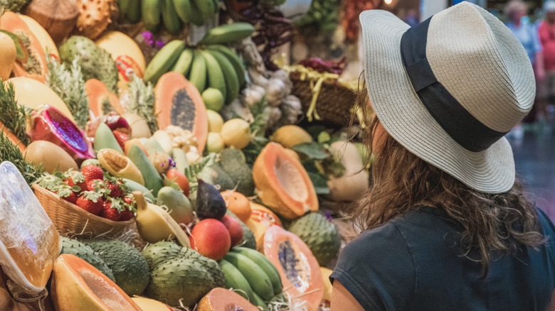woman looking at display of tropical fruits