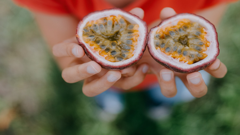 girl holding two halves of passion fruit