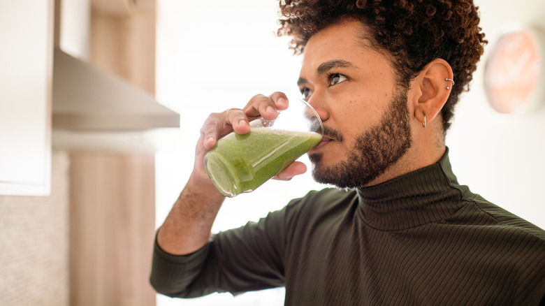 man drinking a green smoothie