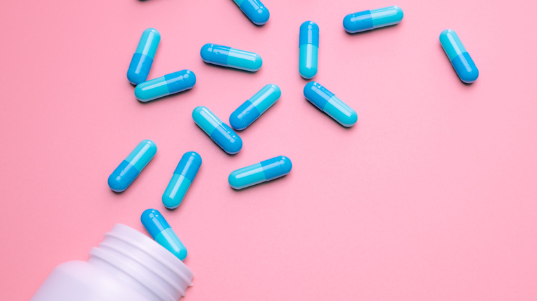 Bottle with spilled blue capsules