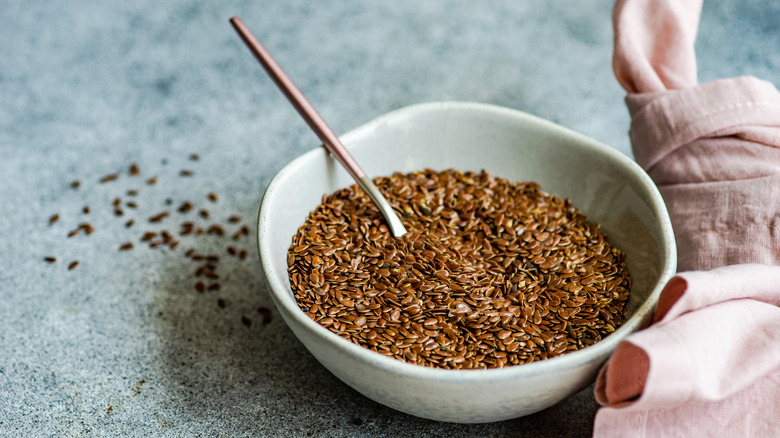 A small bowl of flaxseeds on a slate blue table