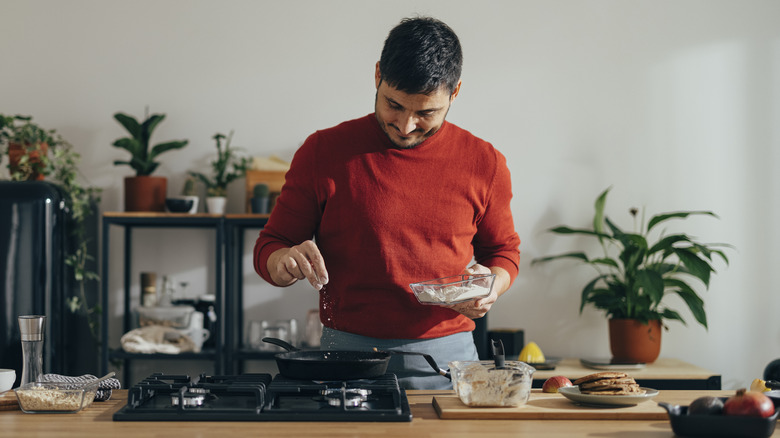 man adding spices to what he's cooking