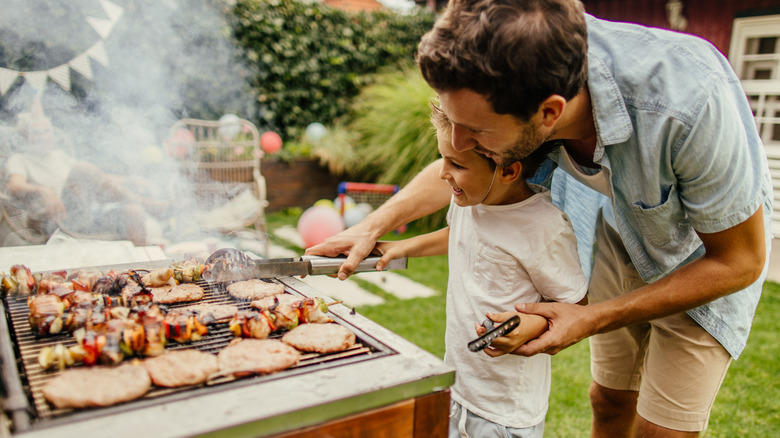 Father and son grilling meat