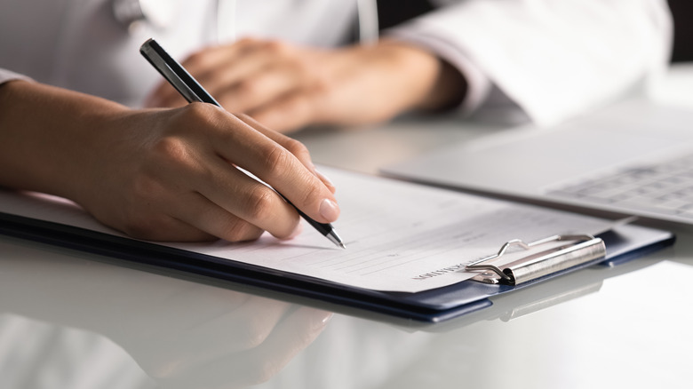 Doctor writing on clipboard
