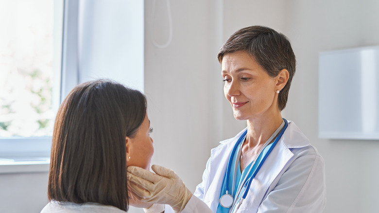 Doctor examining woman's sore throat