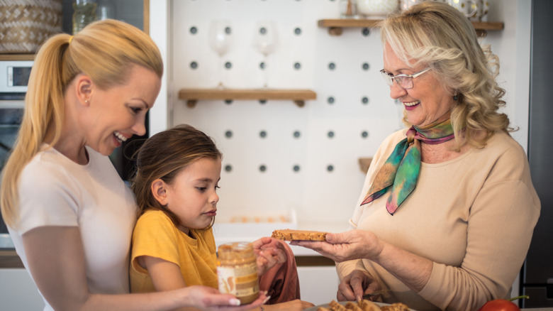 older woman sharing a peanut butter sandwich with child