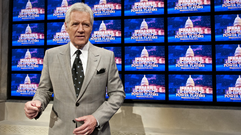 Alex Trebek in front of the Jeopardy screens