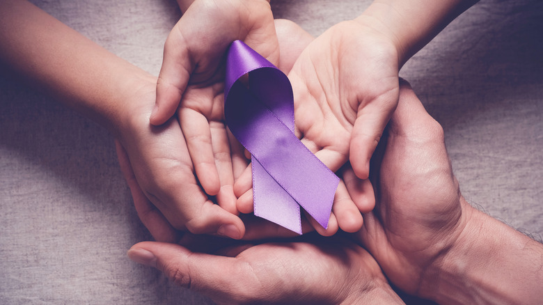 Hands holding a purple pancreatic cancer ribbon