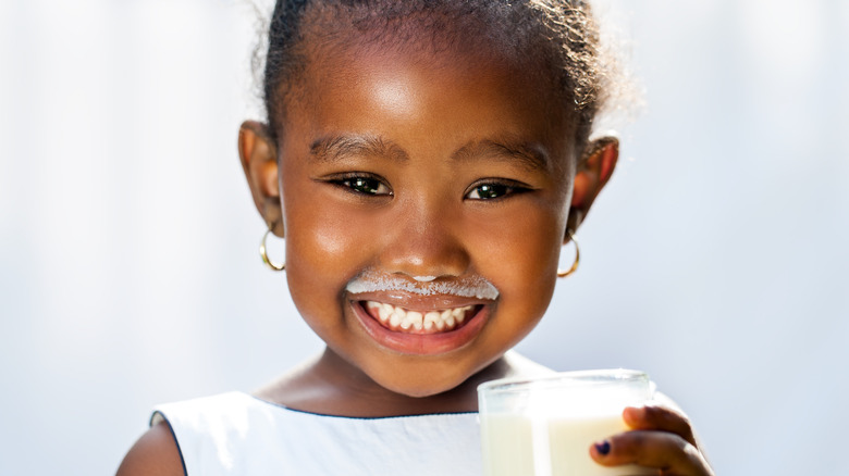 a little girl smiles with a milk mustache