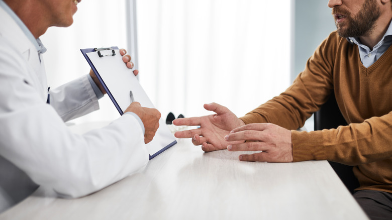 Doctor with clipboard speaking to patient