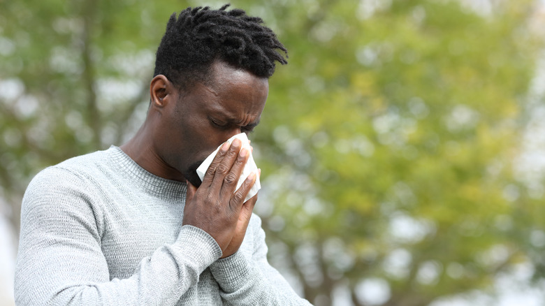 Man sneezing outdoors