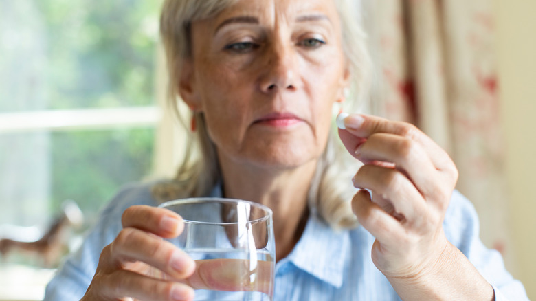 A woman taking aspirin with a glass of water