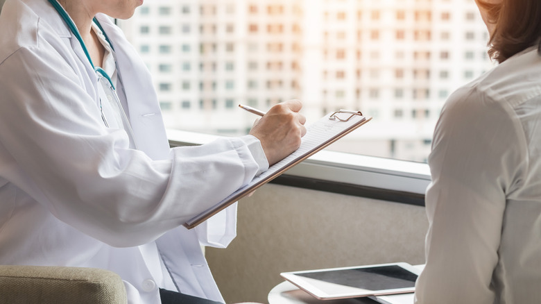 Doctor writing on clipboard during patient visit