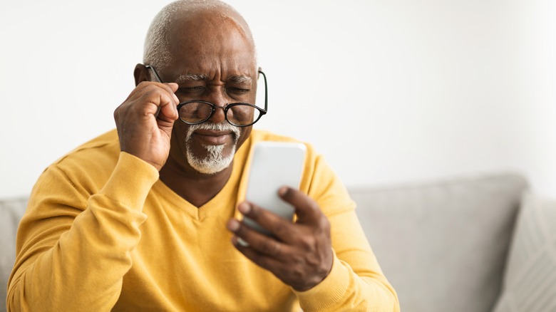 older man squinting to see phone