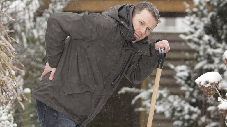 Man with back pain shoveling snow