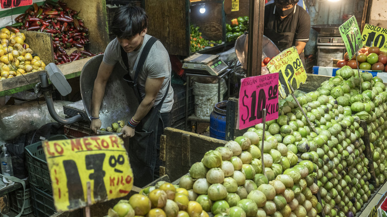 man taking tomatillos out of box in store