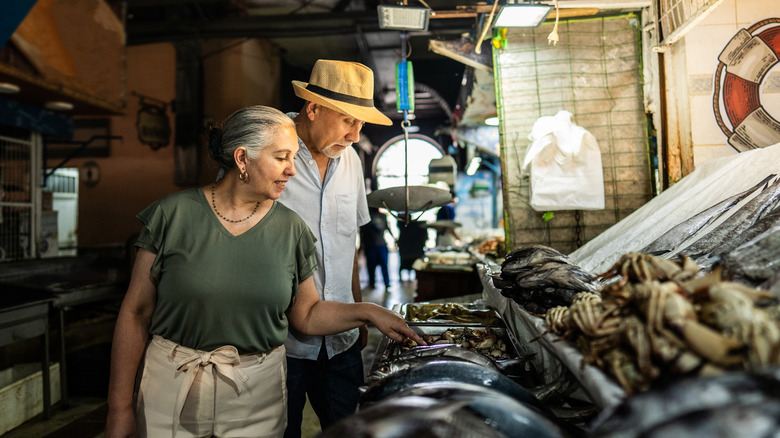 An older couple choosing fish at a fish market