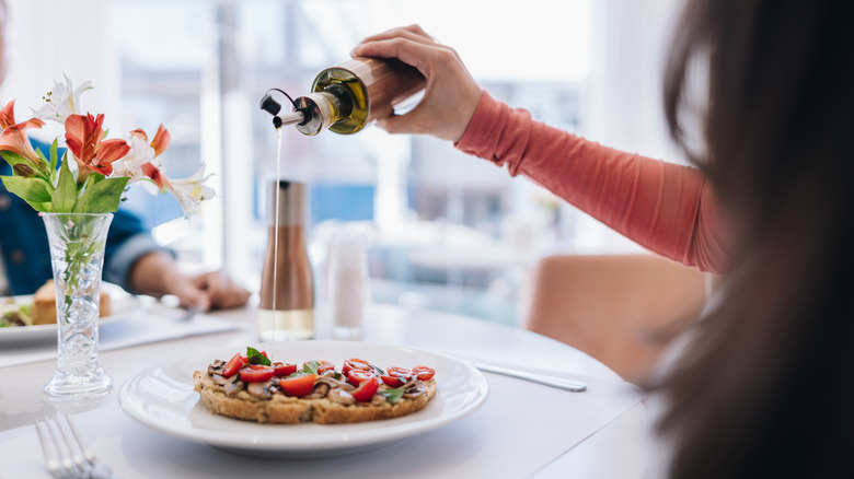 A woman pouring oil over her bruschetta