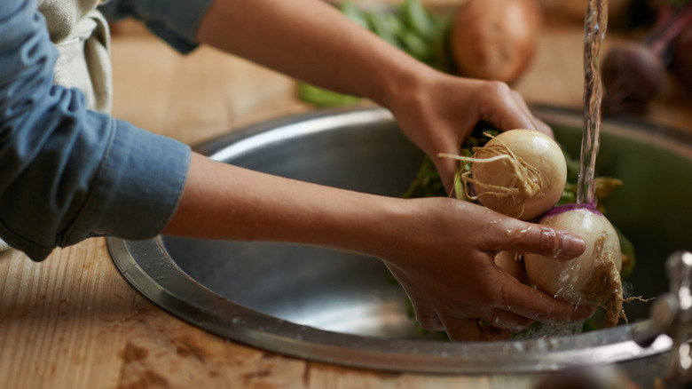 A woman washing turnips in the sink