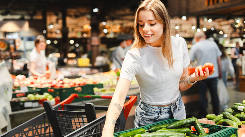 A young woman reaching for vegetables in the produce section of a market