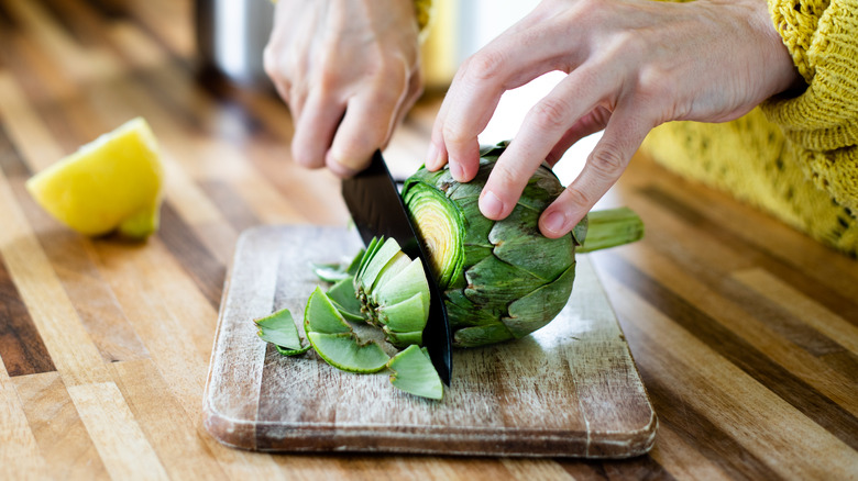 Woman chopping artichoke and lemon