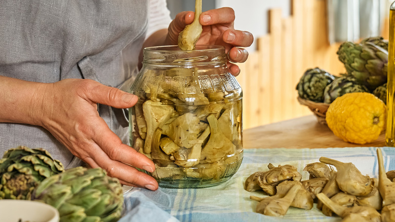 Woman handling a jar of pickled artichokes