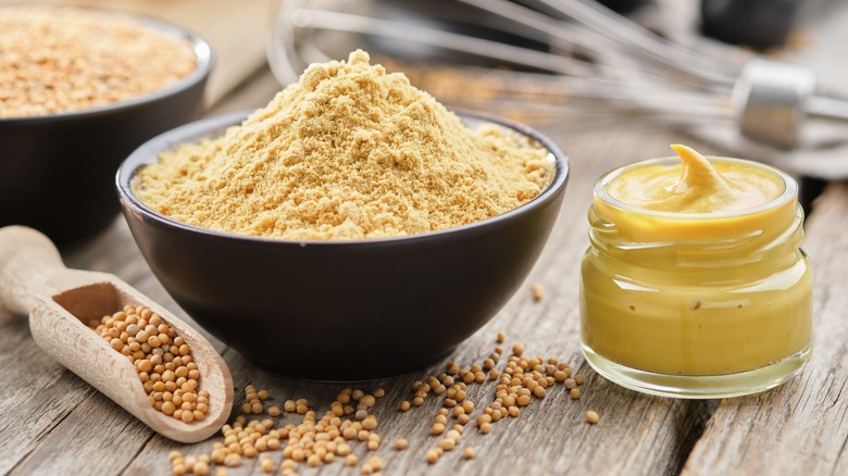 Jar of mustard sauce and bowl of powdered mustard seed