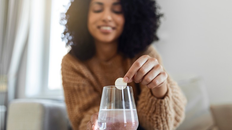 Woman dropping antacid into water glass