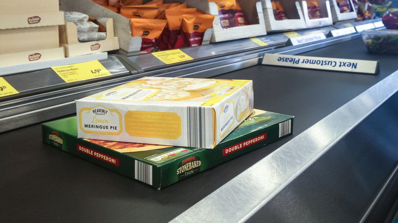 A frozen pizza and pie on a conveyor belt