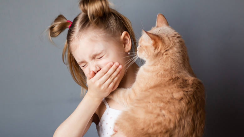 child holding a cat and sneezing