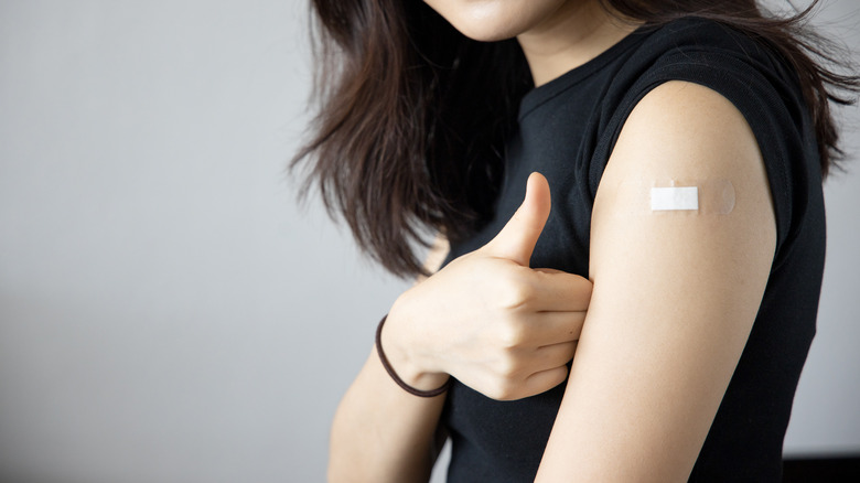 Women making thumbs up sign next to her arm that has a bandage