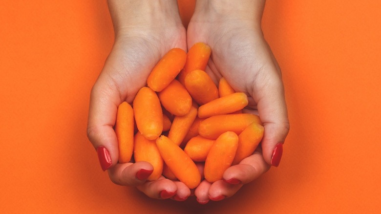 woman holds baby carrots