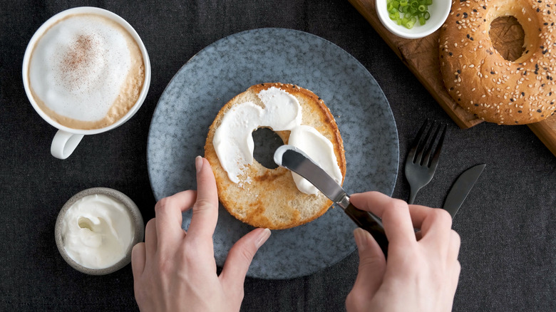 spreading cream cheese on bagel