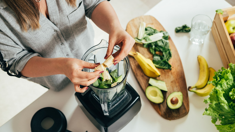 Woman dropping bananas into blender