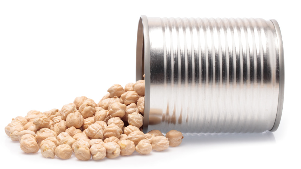 Chickpeas spilling out of a tin can tipped on its side